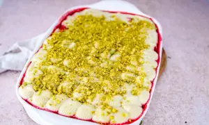 Ein cremiges Pistazien Tiramisu in einer weißen Auflaufform, bestreut mit gehackten Pistazien.