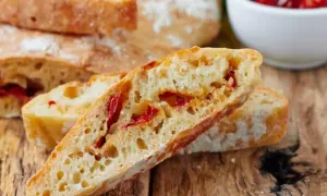 Frisches Ciabatta mit Tomaten, auf einem rustikalen Holztisch.