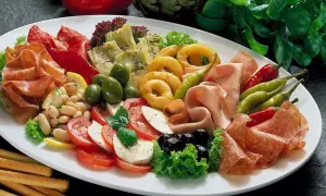 Eine reichhaltige Antipasti-Platte mit Wurst, Käse, Gemüse, Oliven und Brotstangen.