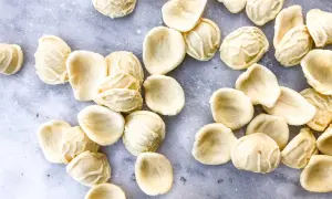 Orecchiette, die "kleinen Ohren" der Pasta, liegen auf grauem Marmor. Die Aussprache ist einfach: Oh-reck-ee-ette.