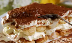 Ein Stück tiramisu originale, mit Löffelbiskuit, Creme und Kakaopulver bestäubt.