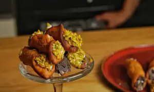 Ein Glasständer voller Cannoli, bestreut mit Pistazien und Schokolade. Ein köstliches Cannoli-Rezept zum Nachmachen.