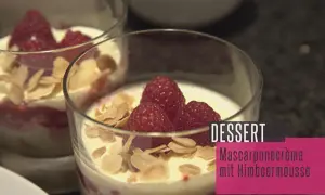 Zwei Gläser mit Himbeer-Mascarpone-Creme, garniert mit frischen Himbeeren und Mandelblättchen. Ein köstliches Dessert.
