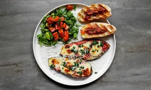 Gegrillte Auberginenhälften mit geschmolzenem Käse, Bruschetta und einem frischen Salat – perfekt für einen italienischen Abend.