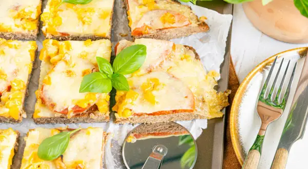 Herzhafte hackfleischpizza vom blech, Landfrauen-Art, mit Tomaten und Käse überbacken, garniert mit frischem Basilikum.