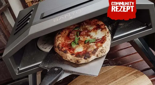 Eine frisch gebackene Pizza wird aus einem Santos Pizzaofen auf eine Pizzaschaufel gehoben.