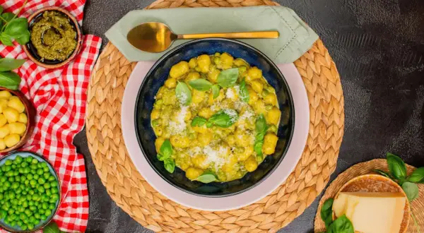 Gnocchi mit Erbsen und Basilikum-Pesto, garniert mit Parmesan. Ein köstliches Gericht, das Lust auf mehr macht.