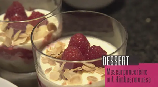 Zwei Gläser mit Himbeer-Mascarpone-Creme, garniert mit frischen Himbeeren und Mandelblättchen. Ein köstliches Dessert.
