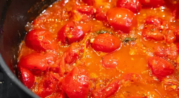 Frische Tomaten köcheln in einer Pfanne zu einer aromatischen Tomatensauce.