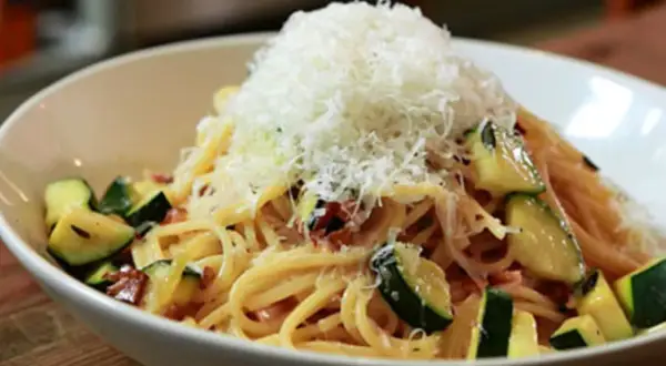 Spaghetti mit Zucchini und Speck, gekrönt mit frisch geriebenem Parmesan. Eine köstliche Zucchini Carbonara.