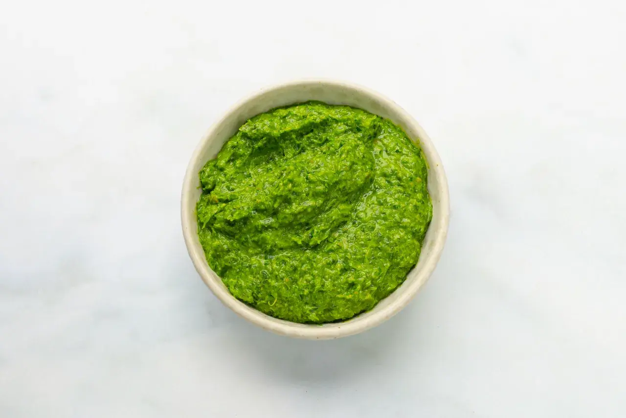 Eine Schüssel mit leuchtend grüner Salsa verde, die frisch und würzig aussieht.