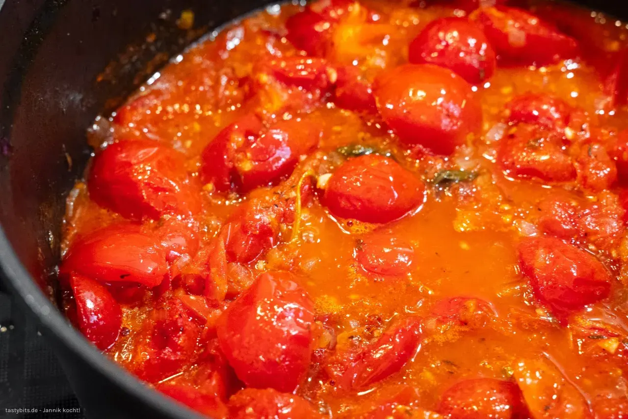 Frische Tomaten köcheln in einer Pfanne zu einer aromatischen Tomatensauce.