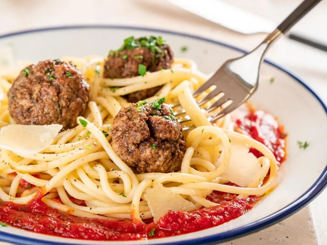 Spaghetti mit drei herzhaften polpetta deutsch, garniert mit Parmesan und Petersilie, serviert mit Tomatensauce.