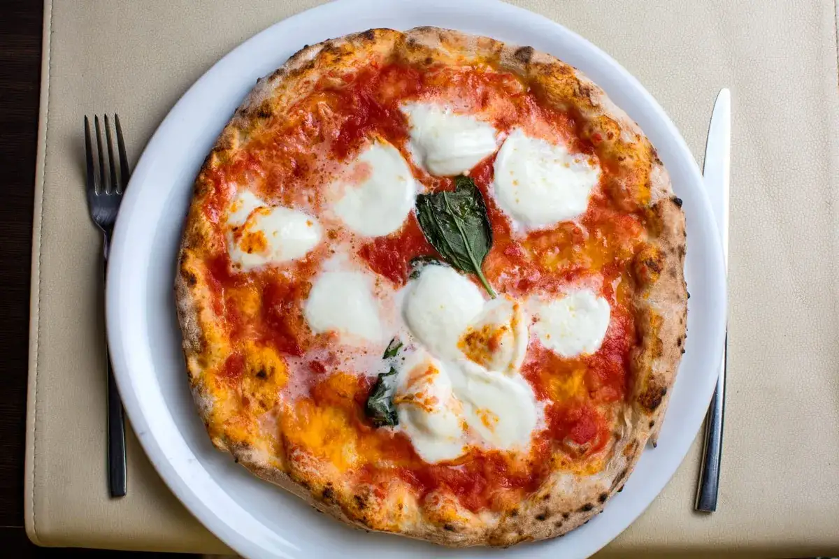 Eine Margherita-Pizza, die nach dem Rezept von Nonna mit bester farina di nonna zubereitet wurde, mit geschmolzenem Mozzarella und frischem Basilikum.