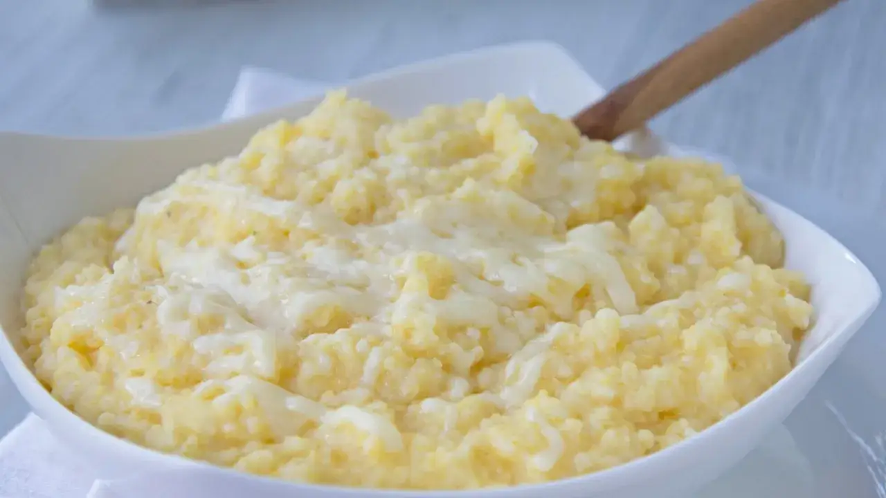 Cremige Polenta Taragna mit geschmolzenem Käse in einer weißen Schüssel, bereit zum Servieren.