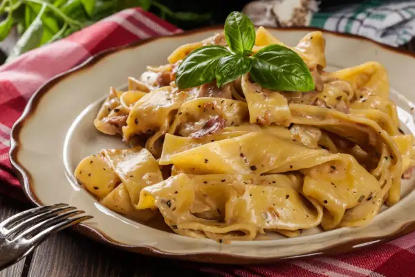 Cremige Pappardelle mit Speck und Kräutern, ein köstliches Pappardelle Rezept, garniert mit frischem Basilikum.