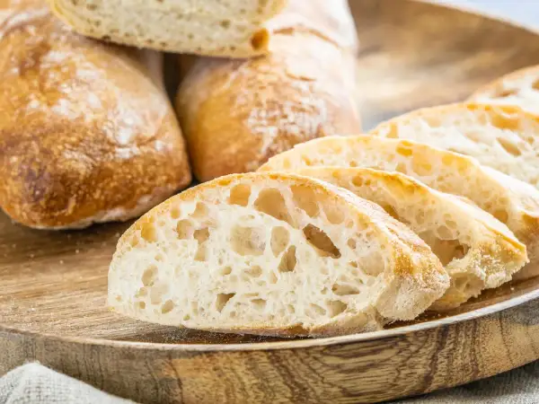 Frisch gebackene Ciabatta-Brote, aufgeschnitten auf einem Holzbrett. Das luftige Innere und die knusprige Kruste sind perfekt für ein Ciabatta Rezept.