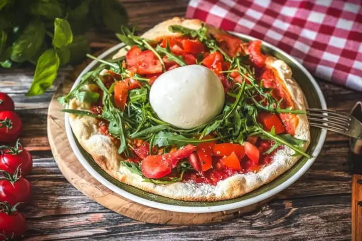 Pizza mit frischen Tomaten, Rucola und einer Kugel Burrata, die Lust auf burrata selber machen macht.