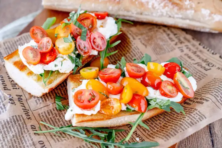 Geröstetes Brot mit Burrata, Kirschtomaten und Rucola.